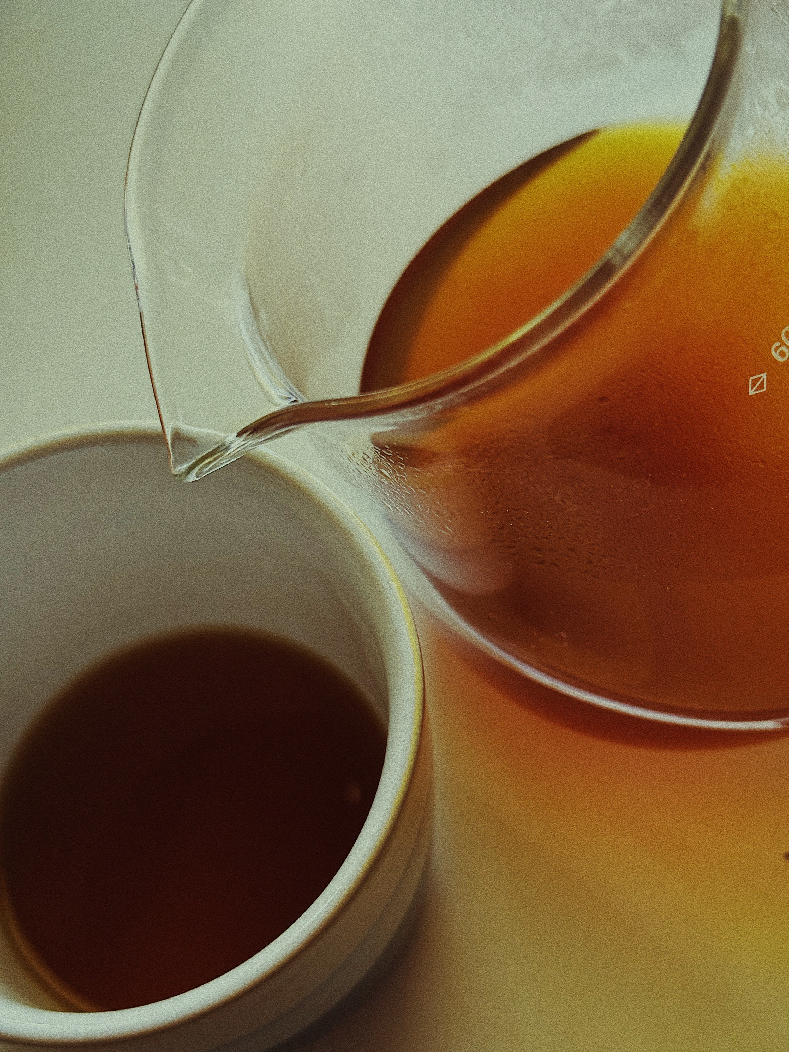 warm-toned photograph of black coffee being poured from a glass carafe into a white cup